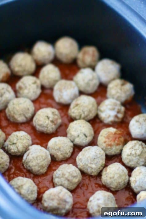 Effortless Slow Cooker Spaghetti and Meatballs 14 layer of spaghetti sauce and layer of frozen meatballs in an oval slow cooker