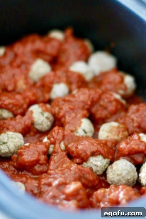 Effortless Slow Cooker Spaghetti and Meatballs 15 spaghetti sauce poured over frozen meatballs in an oval slow cooker