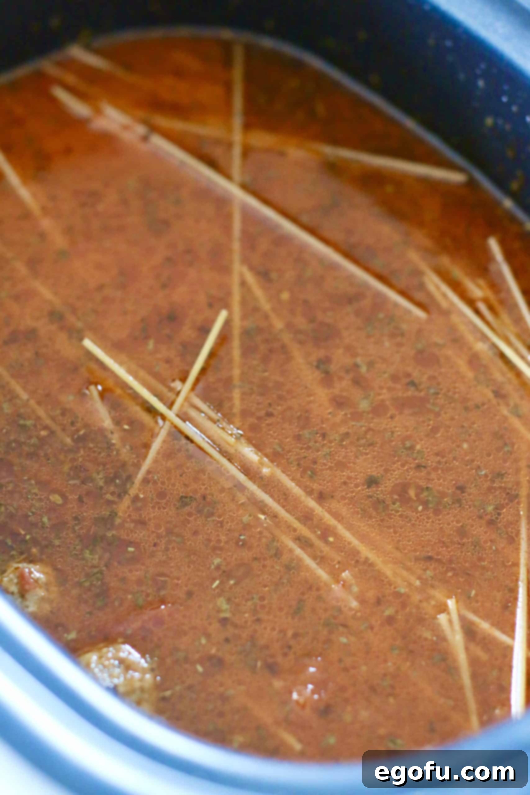 Effortless Slow Cooker Spaghetti and Meatballs 10 Spaghetti noodles fully submerged under the spaghetti sauce and water mixture in the slow cooker.