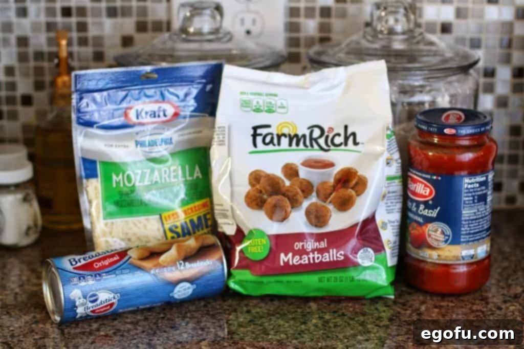 Collection of ingredients for Meatball Sub on a Stick, including a bag of frozen meatballs, breadstick dough, Italian seasoning, mozzarella cheese, and marinara sauce.