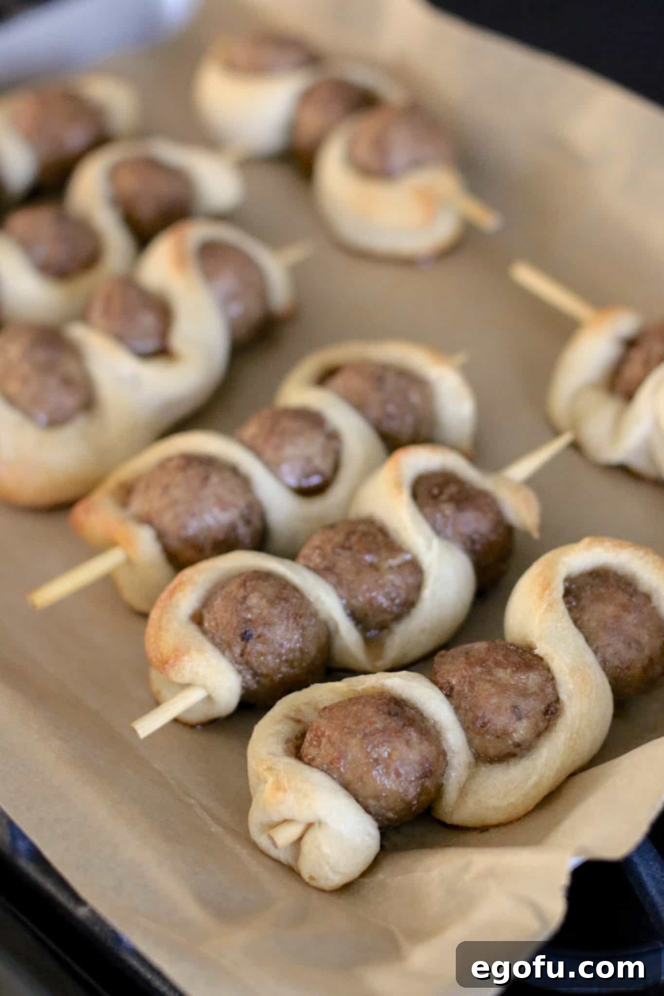 Baked meatball subs on sticks, featuring golden-brown breadsticks and heated meatballs, fresh out of the oven after the initial bake.