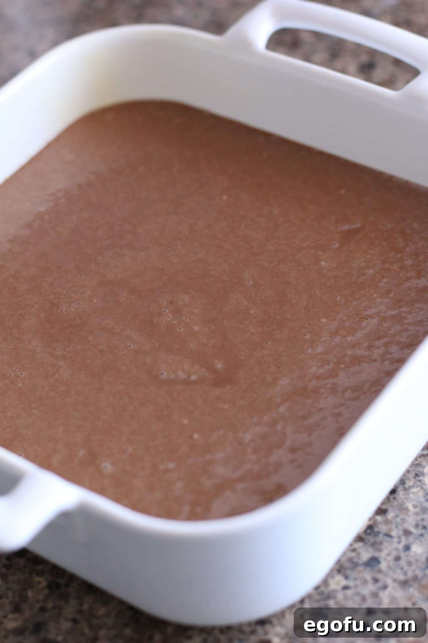 chocolate cake batter poured into a white square baking dish.