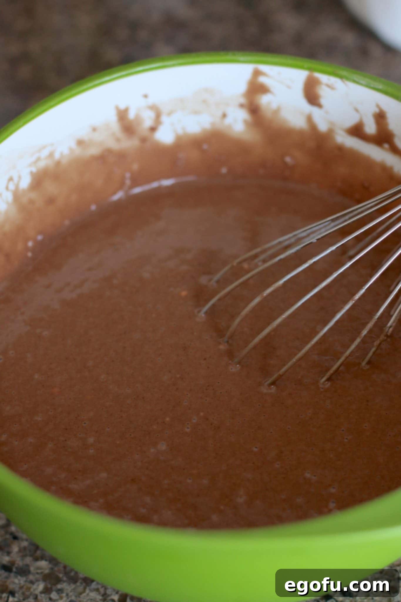 whisking chocolate cake batter in a bowl.