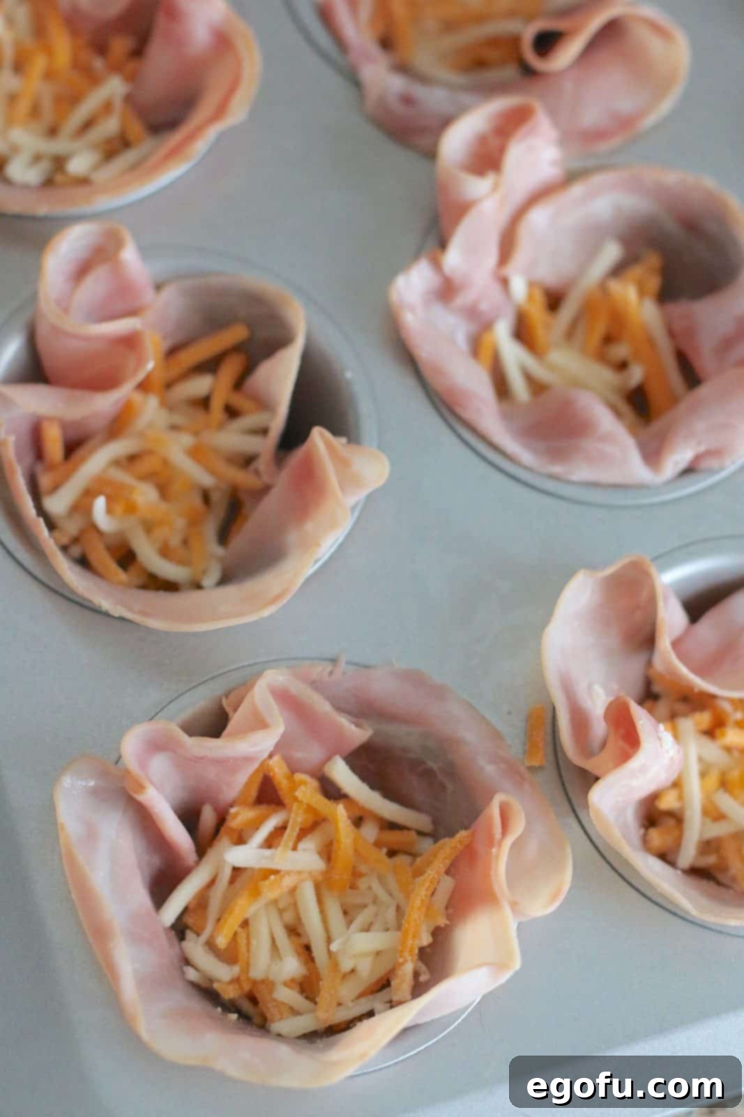Breakfast Ham and Egg Nests 7 shredded cheese added into ham cups in muffin tin.