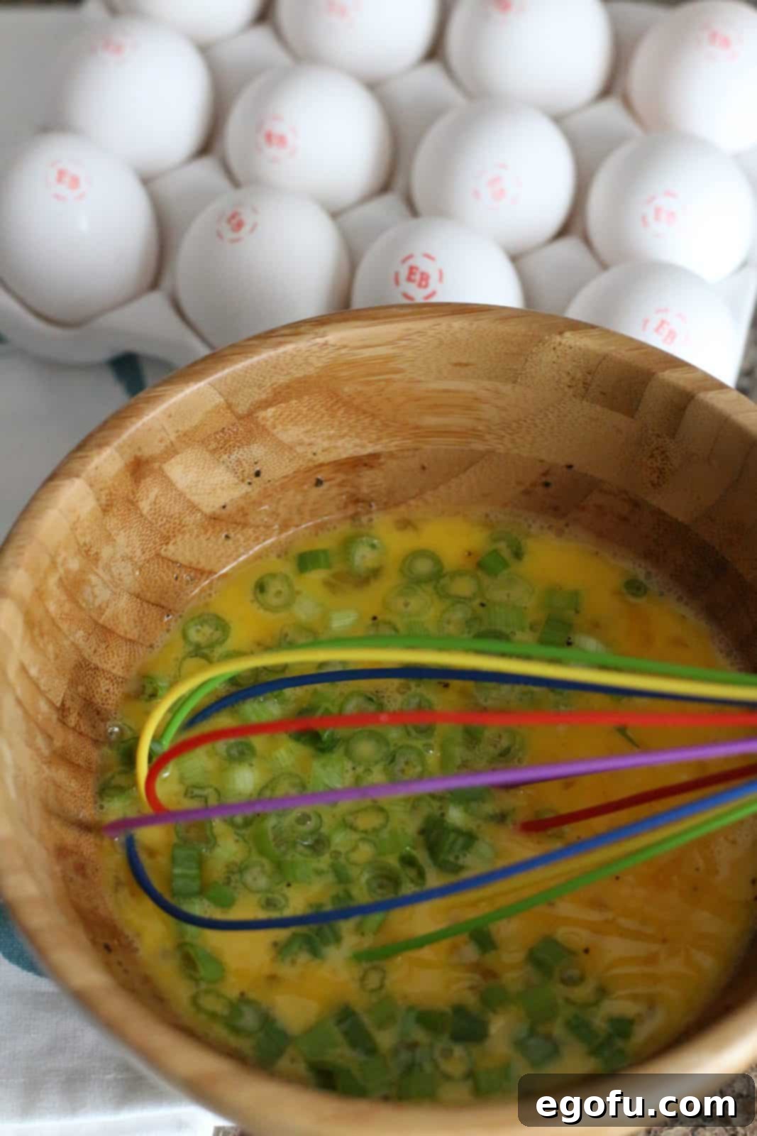 Breakfast Ham and Egg Nests 9 sliced green onions whisked together with eggs in a bowl.