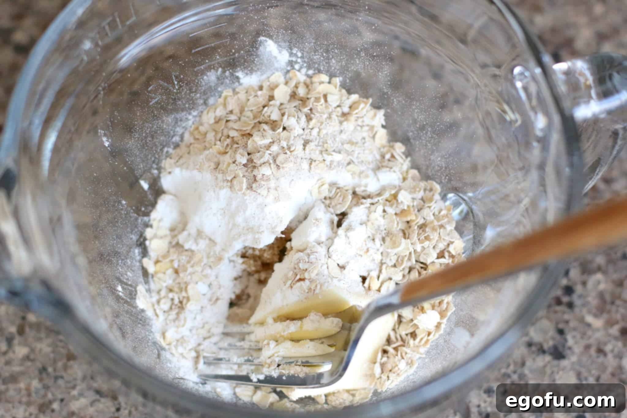 A bowl of freshly prepared oatmeal crumble topping, with a fork, showing its delightful texture and readiness for baking.