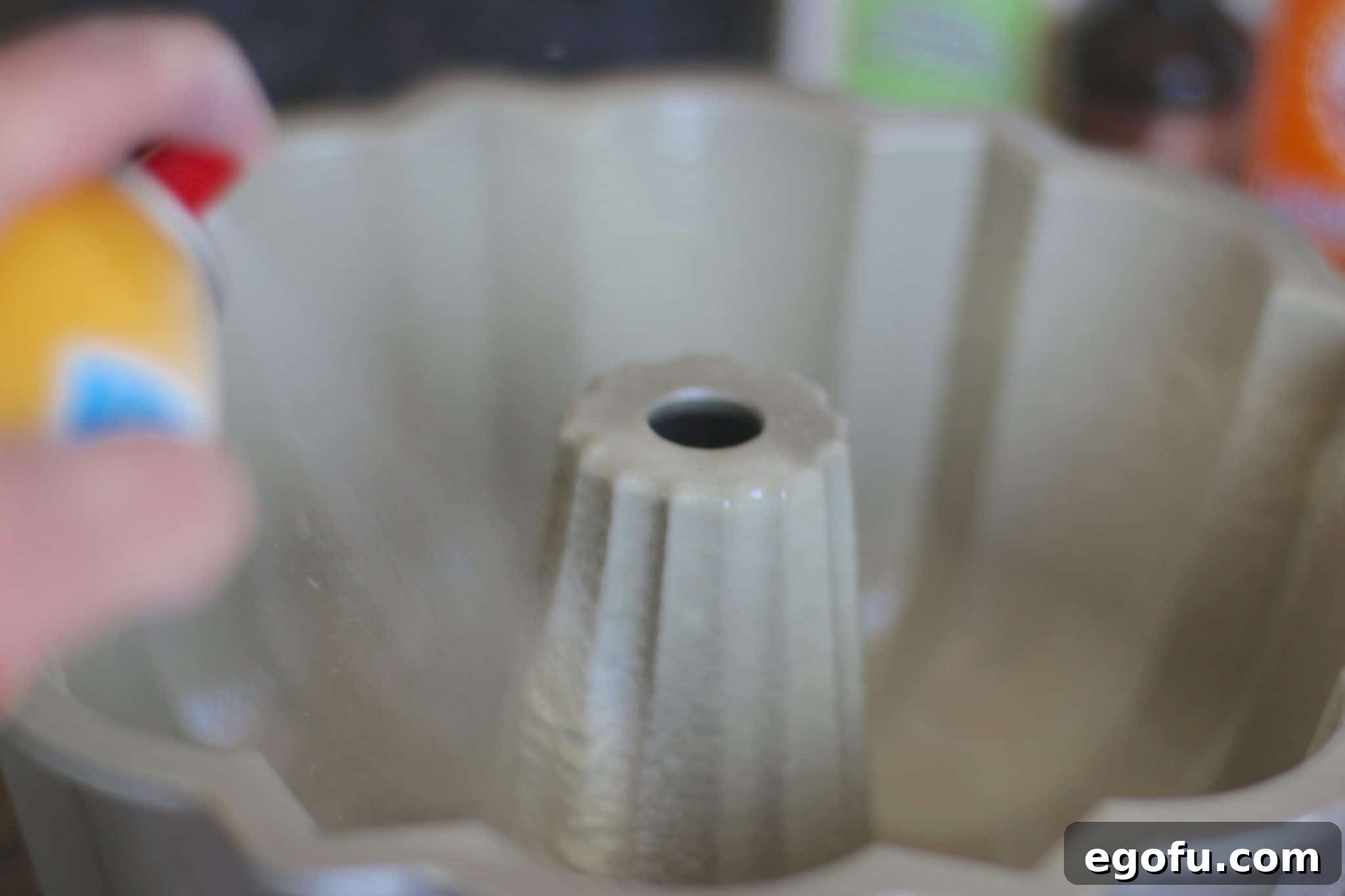 A bundt pan meticulously coated with nonstick baking spray, ready to receive the cake batter.