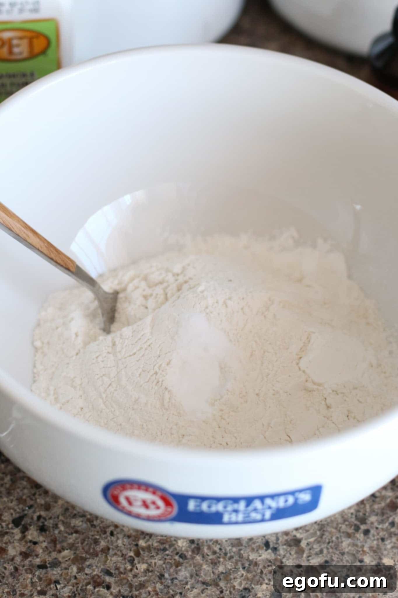 A bowl containing all-purpose flour, baking soda, baking powder, and salt, perfectly combined with a fork, ready for the next step.
