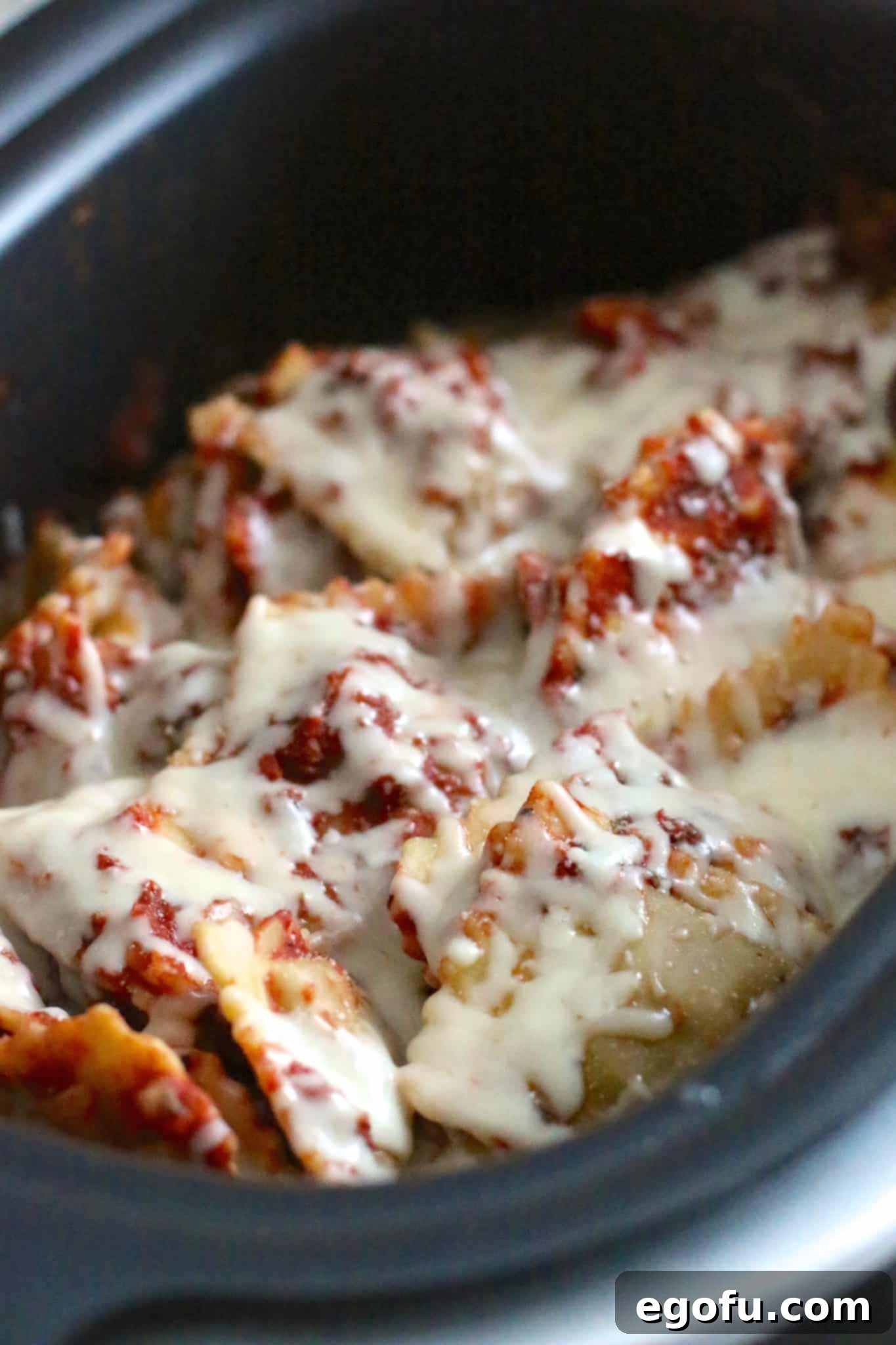 Cooked beef and cheese ravioli tossed in marinara sauce and melted mozzarella cheese, served directly from the slow cooker, glistening and ready to eat.
