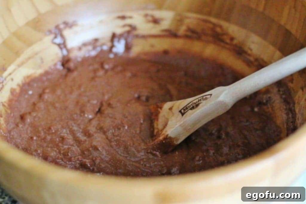 Chocolate chocolate chip muffin mix and milk combined in a bowl, showing the initial mixing stage.