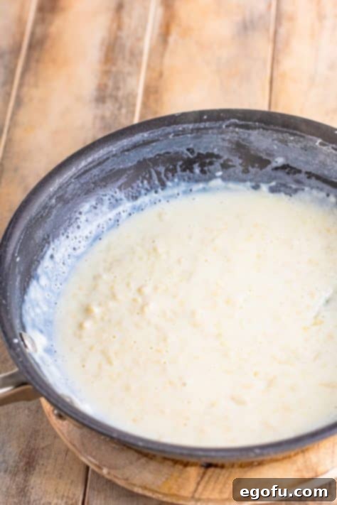 Soul-Warming Chicken and Noodles 14 Milk and all-purpose flour being whisked together in a pan to form a smooth roux.