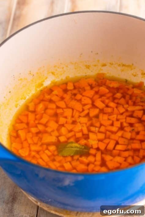 Soul-Warming Chicken and Noodles 10 Diced carrots and a bay leaf simmering in broth within a large pot.