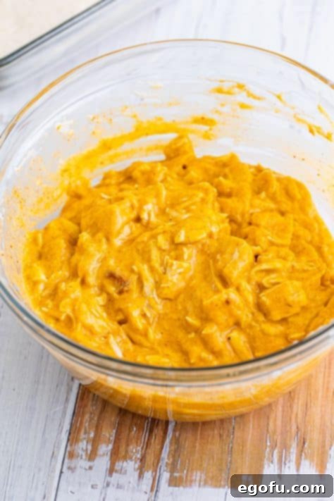 A mixing bowl with enchilada sauce, cream of chicken soup, diced chicken, taco seasoning, and 1 cup shredded cheese.
