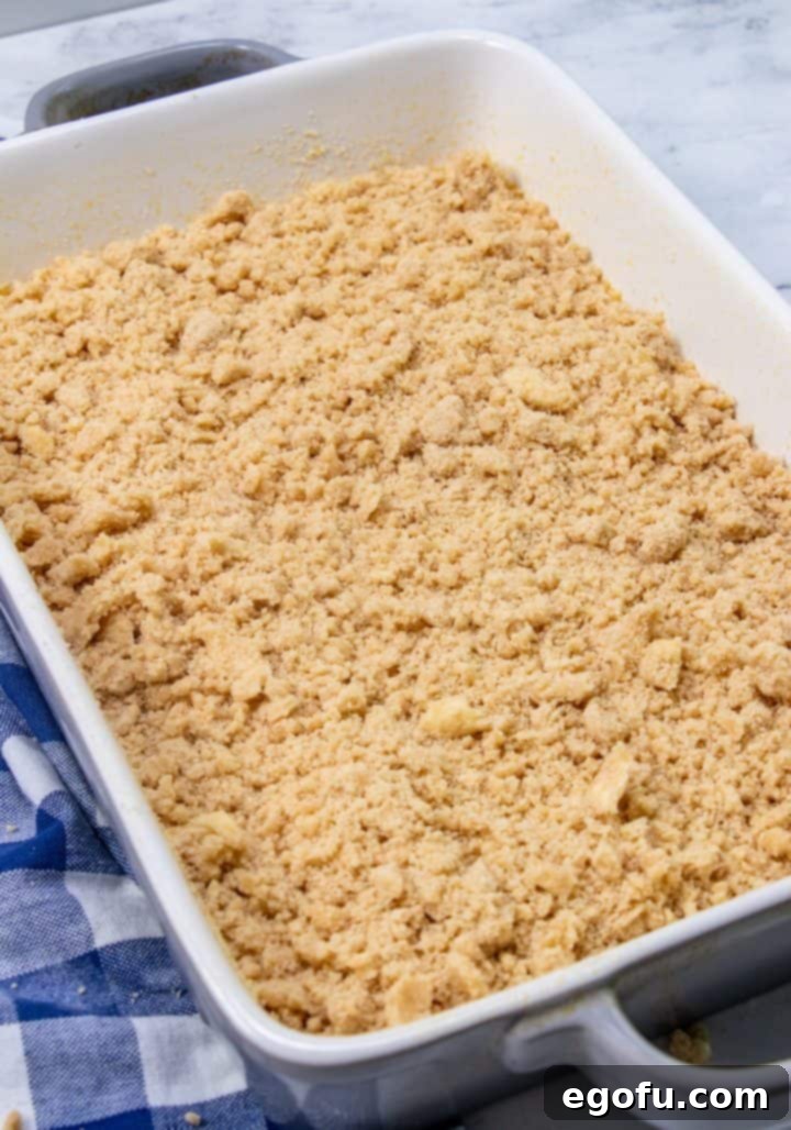 A generous layer of brown sugar crumb mixture evenly sprinkled over the first half of the banana cake batter in the baking dish.