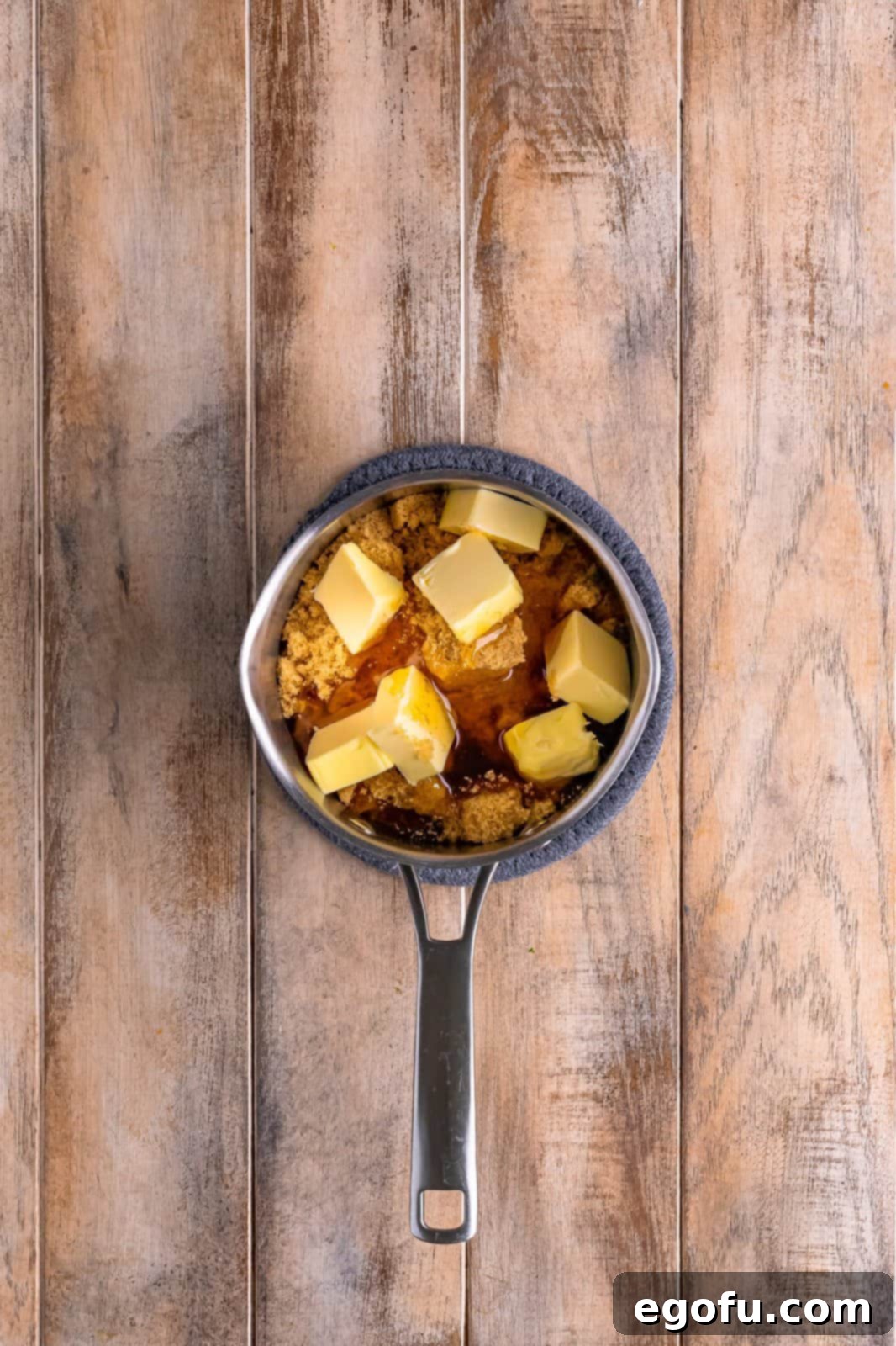 Ingredients for the cinnamon glaze – brown sugar, butter, and honey – combined in a small saucepan over heat, beginning to melt.
