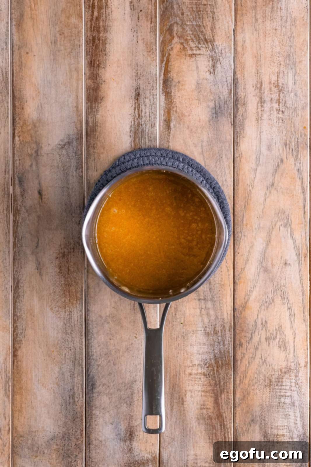 The cinnamon glaze mixture, consisting of brown sugar, butter, and honey, fully melted and combined in a saucepan, showing its smooth, syrupy consistency.