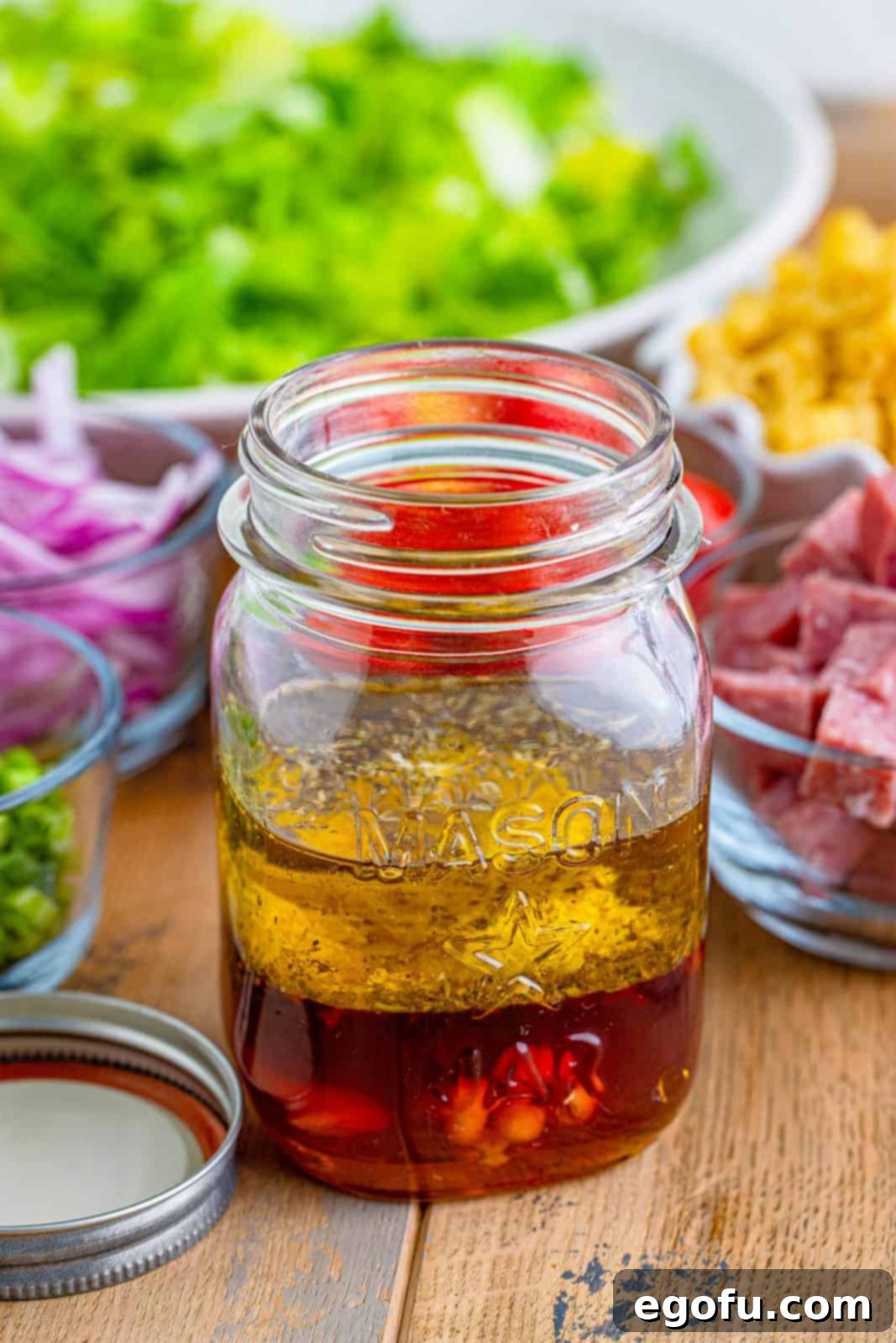 Vibrant Italian Chopped Salad 6 Italian chopped salad ingredients added to a mason jar.