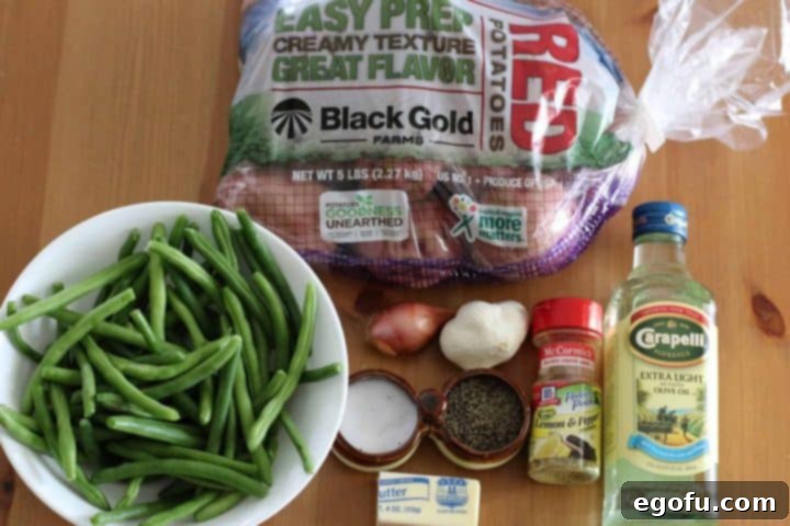 red potatoes, fresh green beans, olive oil, lemon pepper seasoning, shallot, garlic cloves, butter, salt and pepper displayed as ingredients.