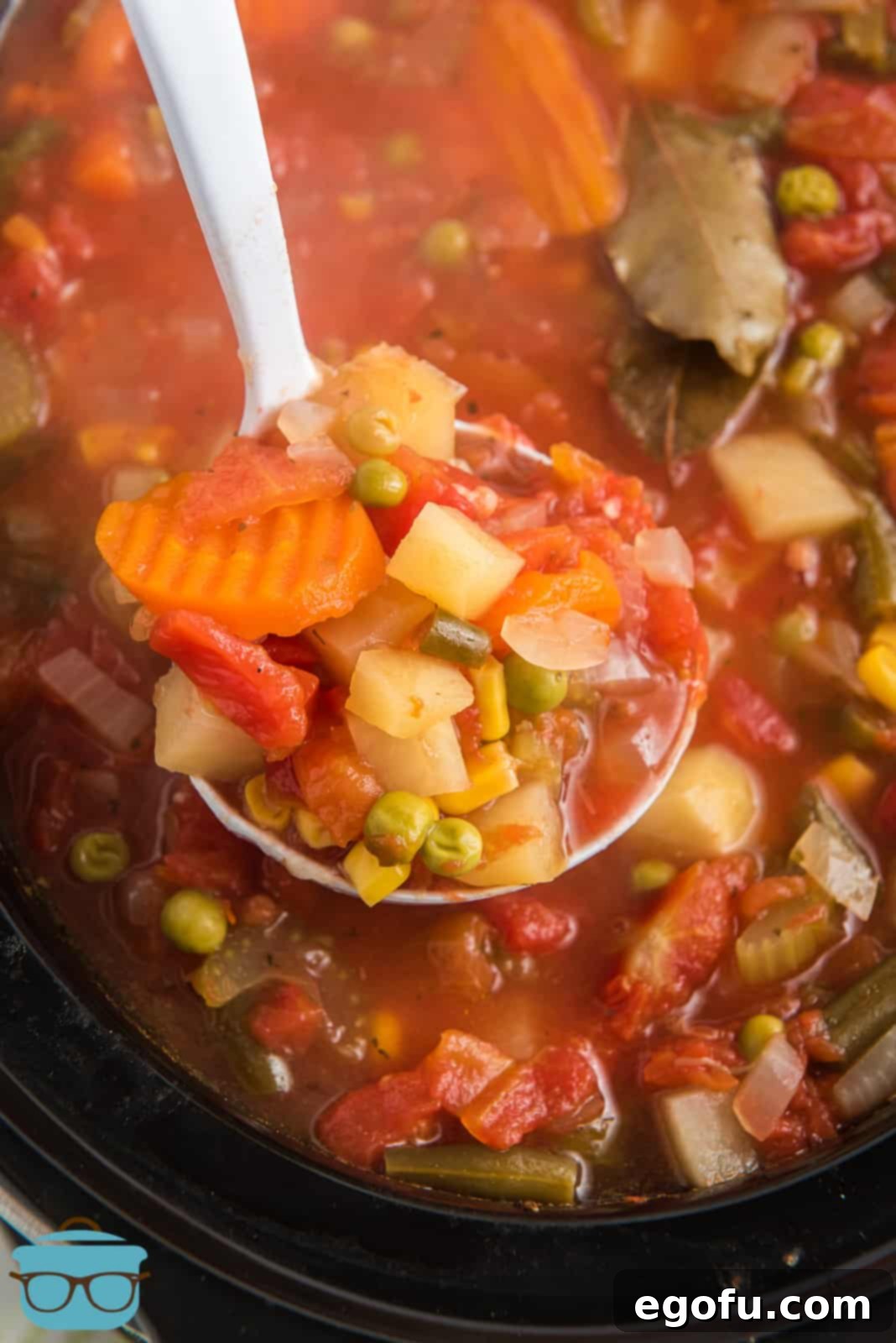 One Pot Comfort Vegetable Soup 2 Metal ladle holding up some of the Crock Pot Vegetable Soup, showcasing its rich texture and colorful vegetables.