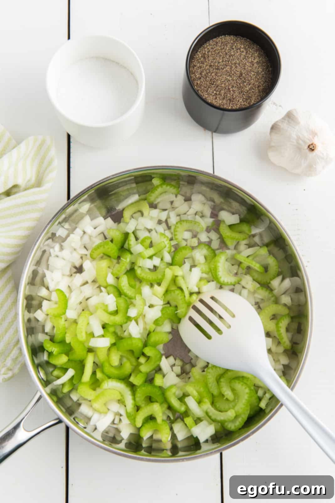 One Pot Comfort Vegetable Soup 5 Olive oil, onions, celery and minced garlic being sauteed in a large pan on the stove.
