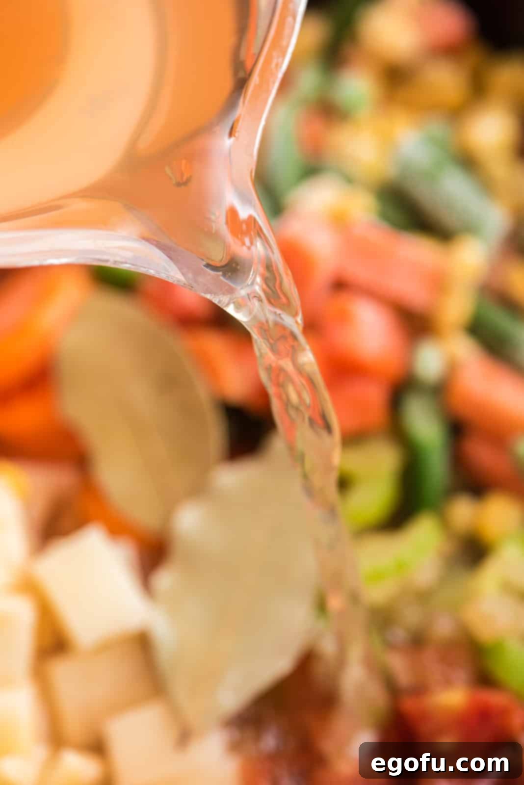 One Pot Comfort Vegetable Soup 7 Vegetable broth being poured into the Crock Pot over the mixed vegetables.