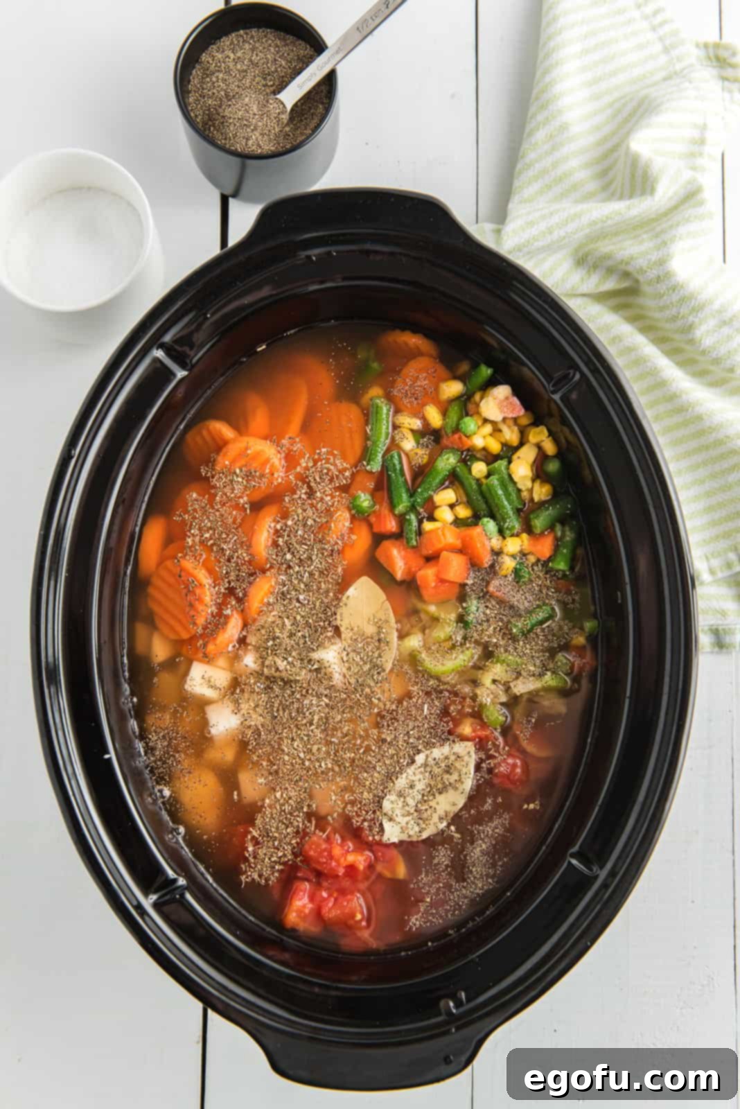 One Pot Comfort Vegetable Soup 8 Two bay leaves and various seasonings like salt, pepper, dried basil, and oregano added on top of the vegetable soup mixture in the Crock Pot.