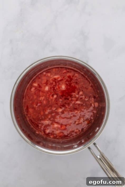 Strawberry glaze mixture simmering in a pan.