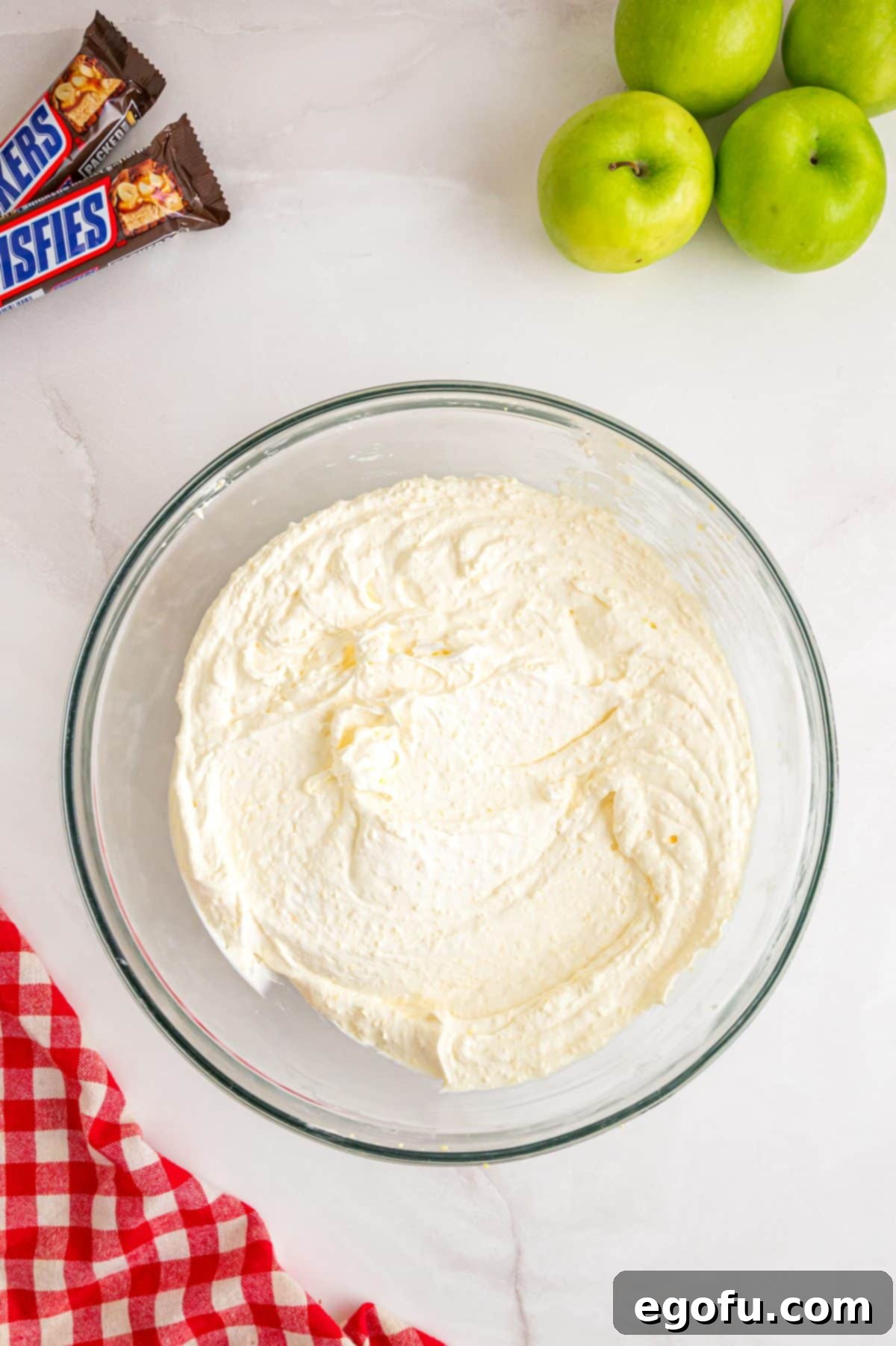 Creamy Snickers Apple Delight 5 Whipped cream being mixed with pudding in a bowl.