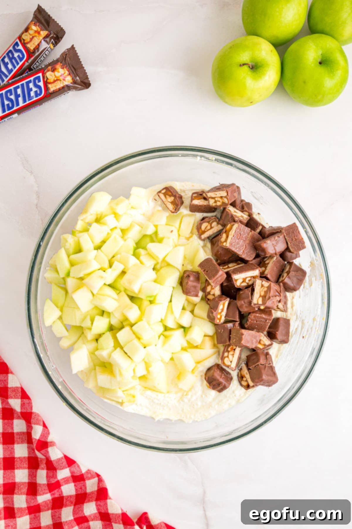Creamy Snickers Apple Delight 6 Snickers and apples being mixed in the Cool Whip and pudding mixture.