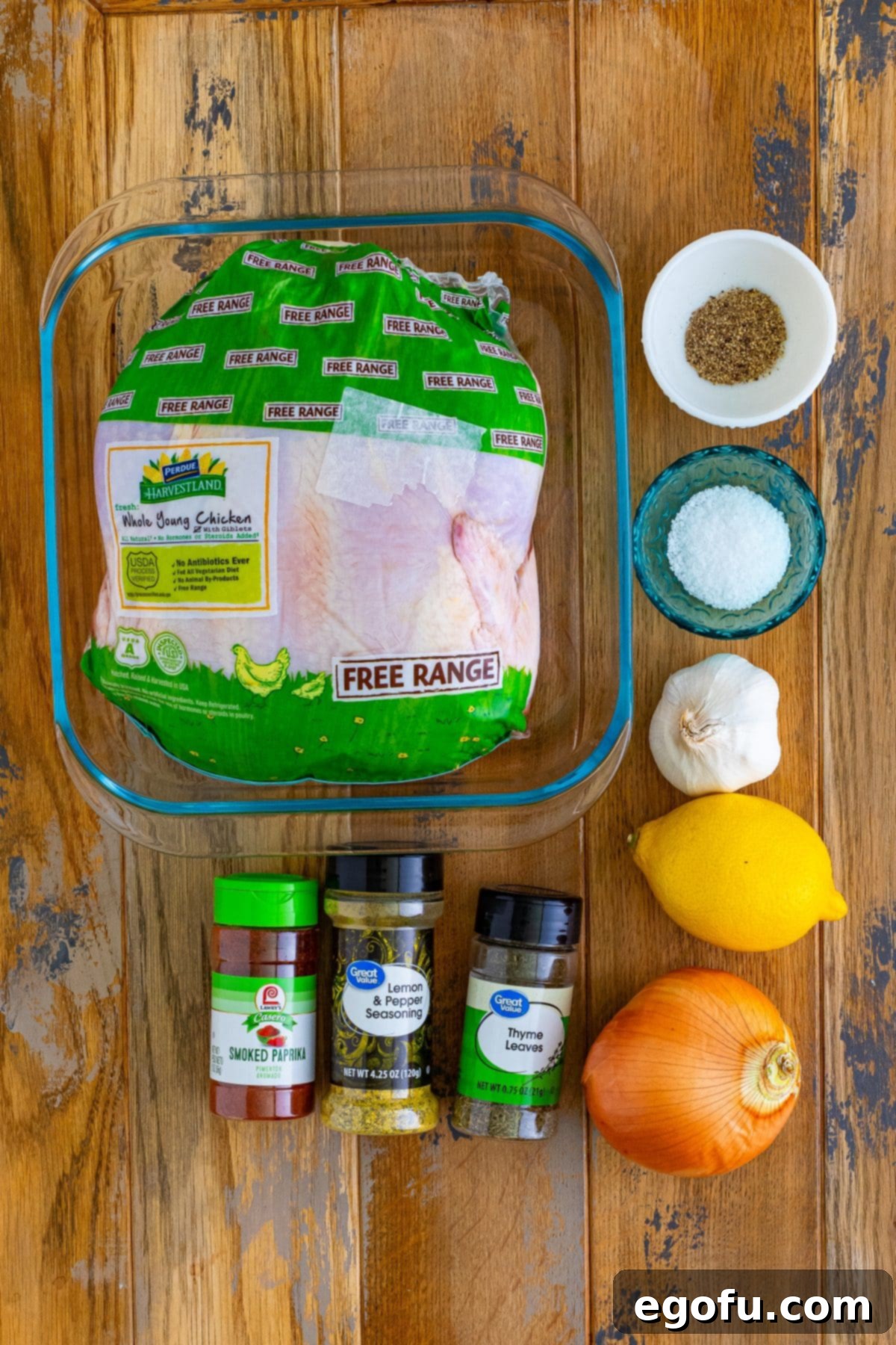 A whole roasting chicken, salt, ground black pepper, paprika, dried thyme, lemon pepper, lemon, garlic, and onion.