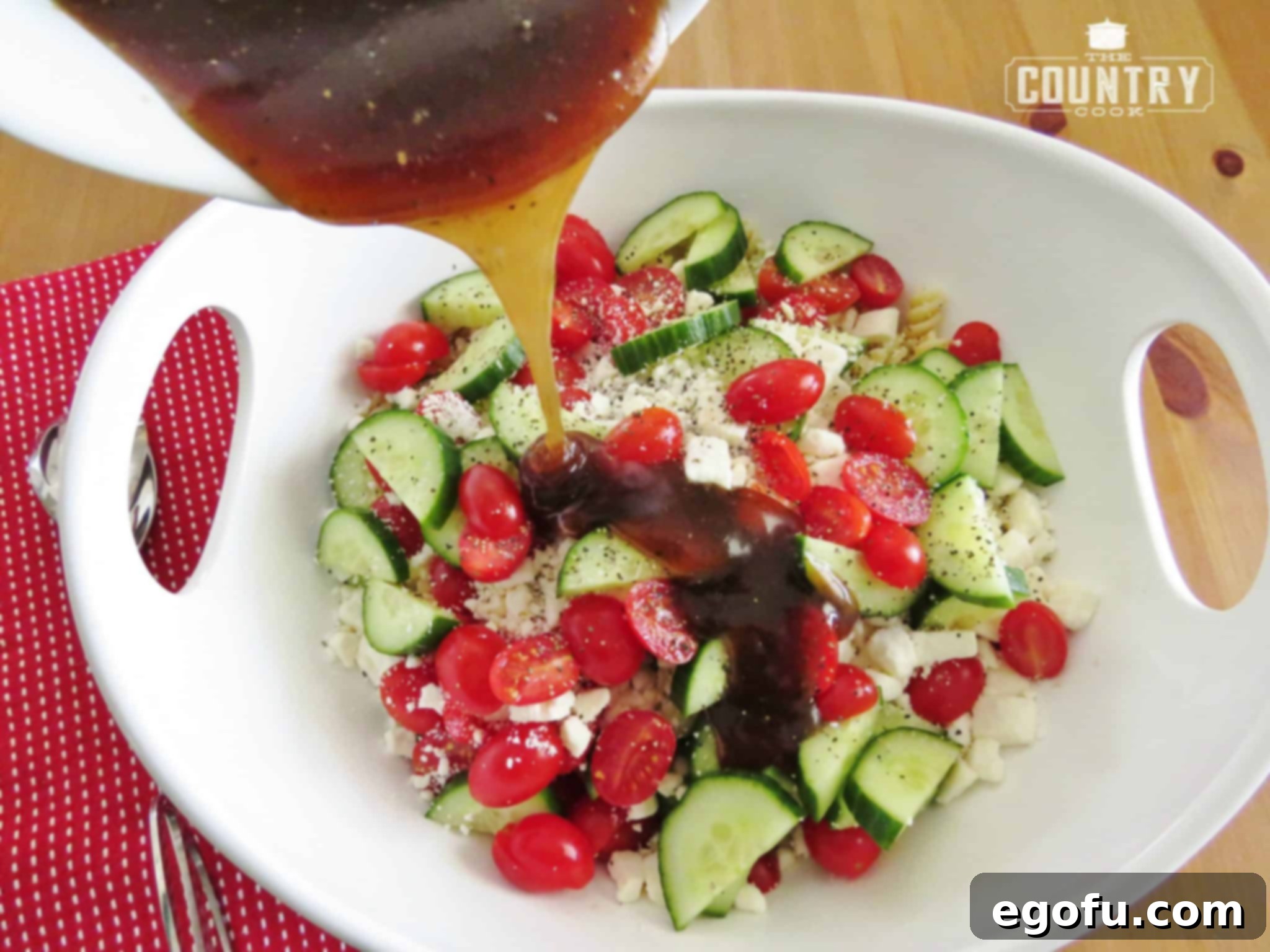 Sweet balsamic dressing being generously poured over a bowl of fresh pasta salad, showcasing the vibrant colors of the ingredients.
