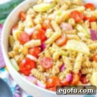 Balsamic vinegar dressing with rotini pasta, feta cheese, cucumbers and feta cheese in a bowl