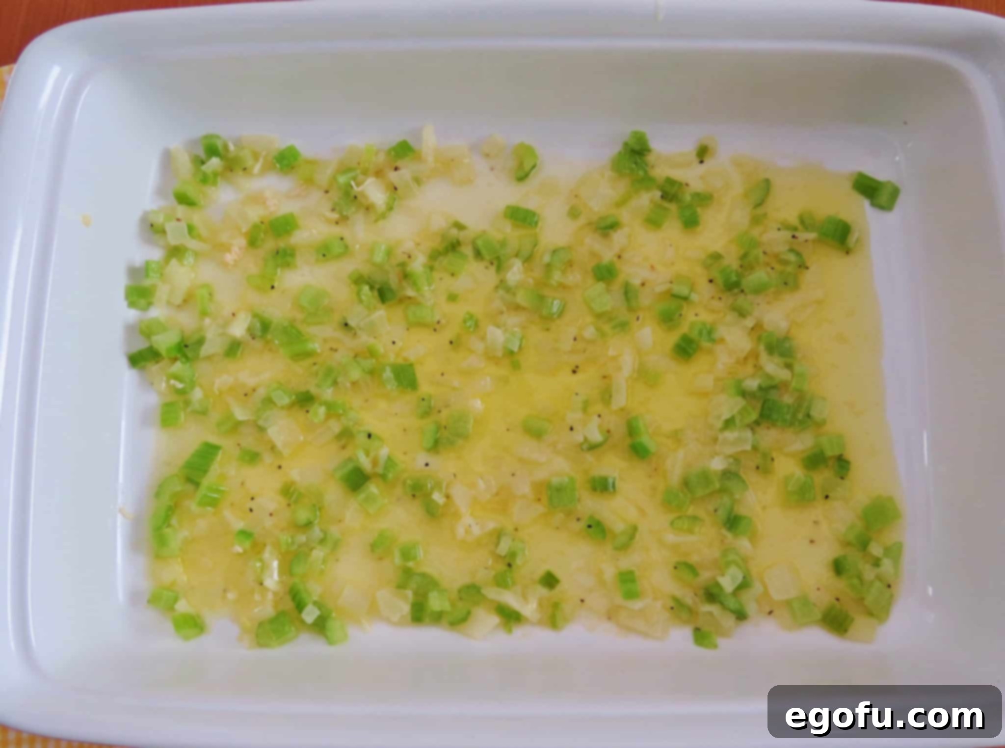 melted butter, cooked diced celery and onion layered into the bottom of a large white baking dish.
