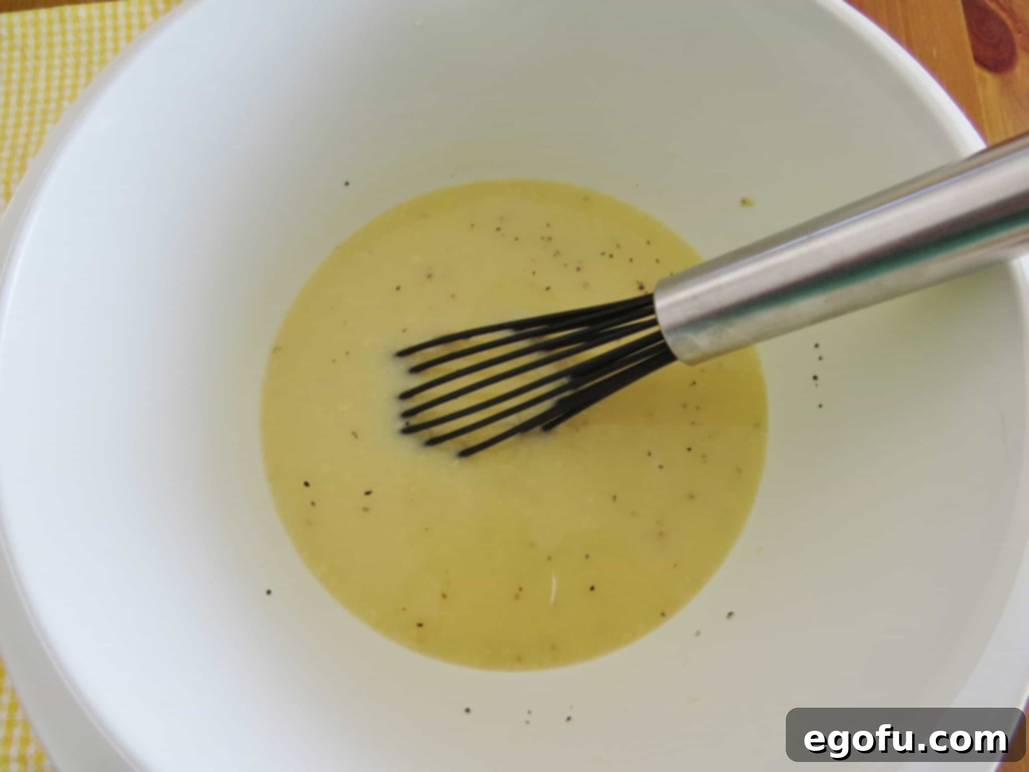 milk and self rising flour whisked together in a white bowl.