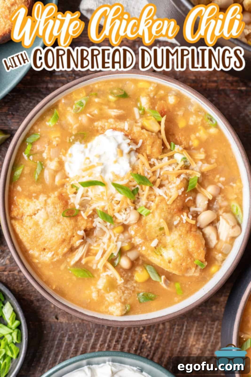 An overhead photo of a white bowl filled with white chicken chili and cornbread dumplings on a rustic wooden surface. 