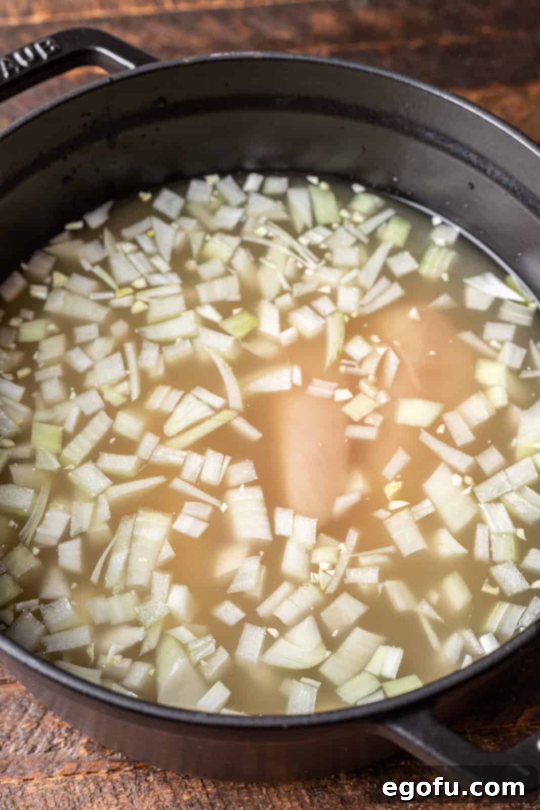 Chicken broth, onion, garlic, and chicken breasts simmering in a large pot, beginning the chili base. 