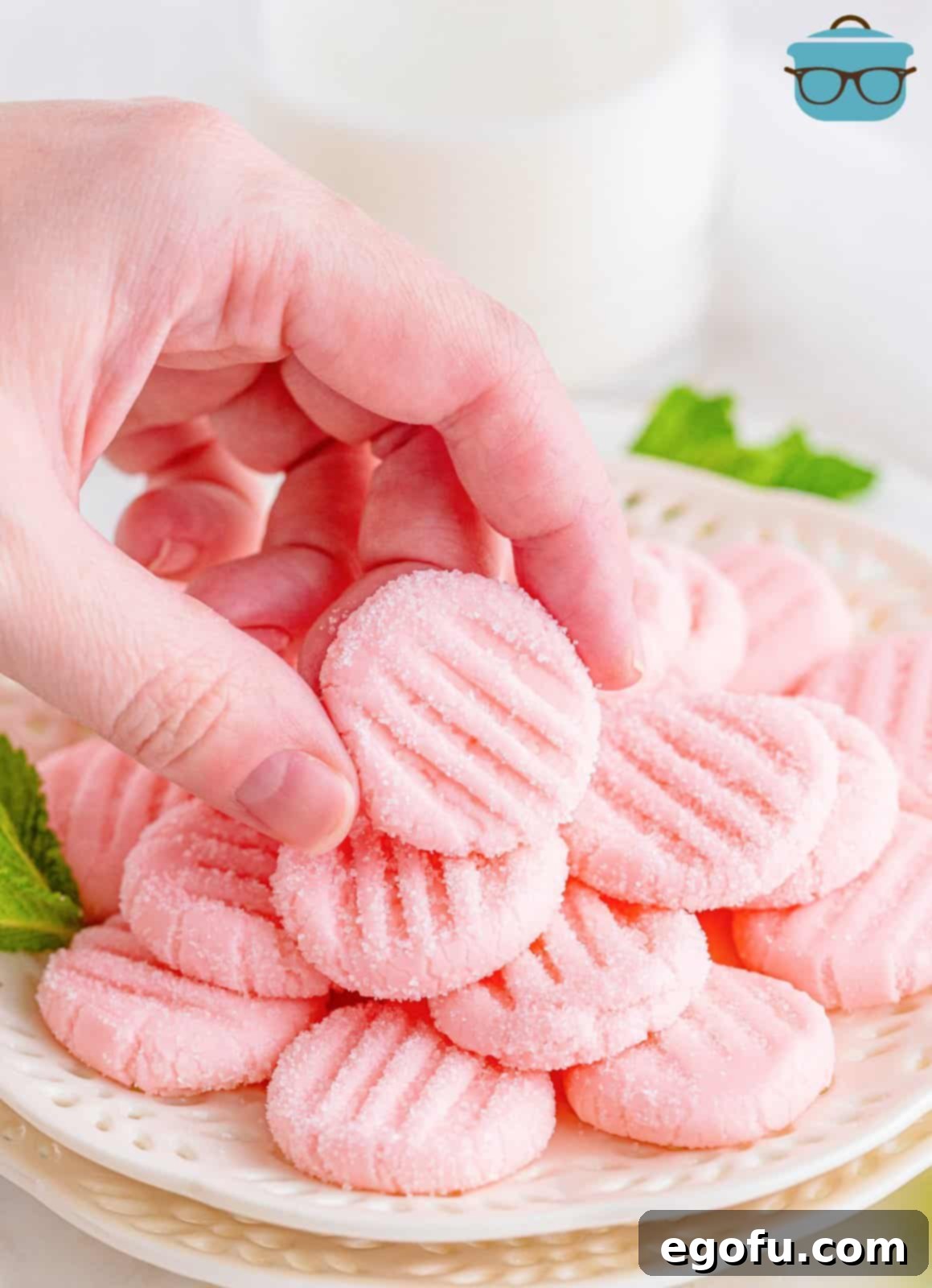 Refreshing Finales 12 A hand carefully picking up a single cream cheese after-dinner mint, showcasing its perfect size and delicate appearance.