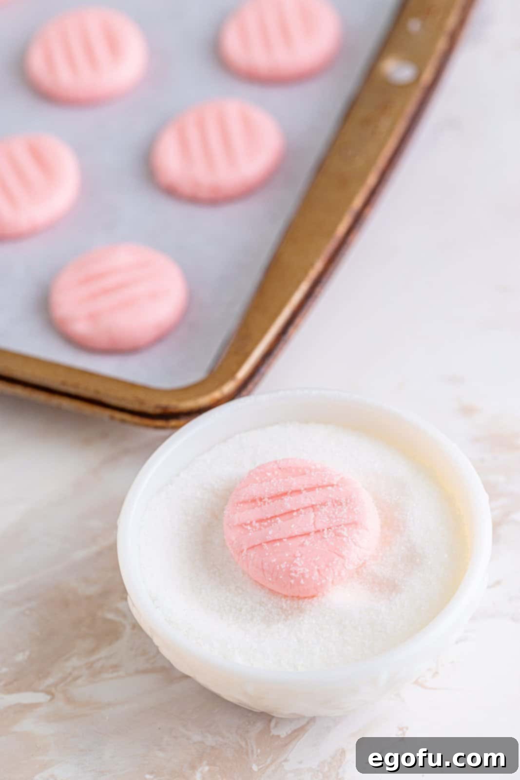 Refreshing Finales 10 A hand rolling a shaped after-dinner mint in a bowl filled with granulated sugar, ensuring an even coating.