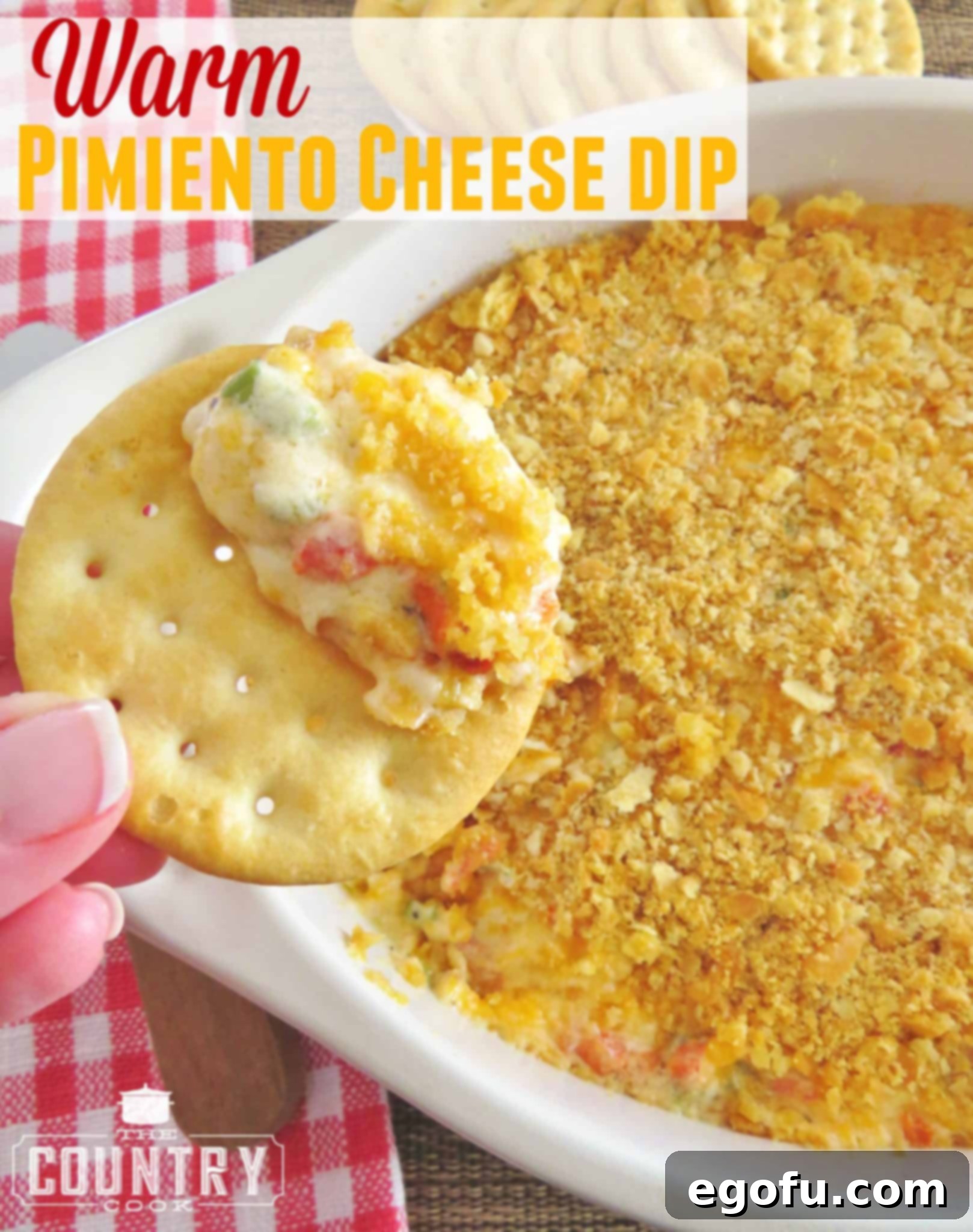 Close-up photo of a buttery cracker generously topped with warm pimiento cheese dip, ready to be enjoyed.