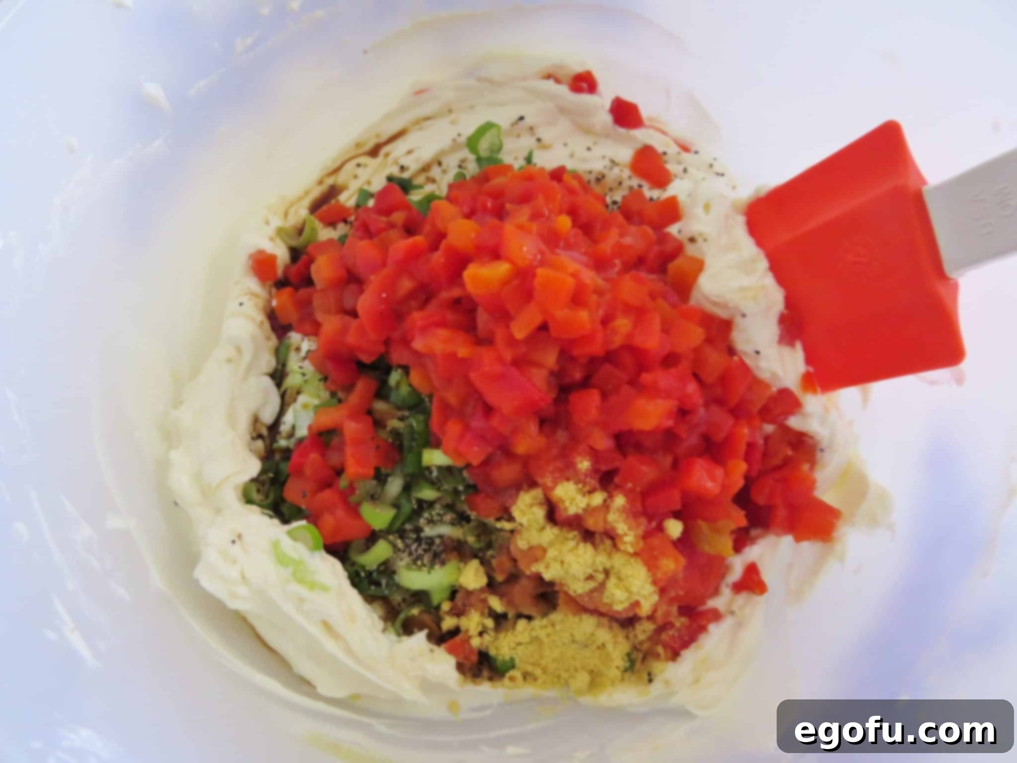 Diced pimientos, dry mustard, freshly chopped green onions, and Worcestershire sauce being added to the creamy mixture in a large bowl.