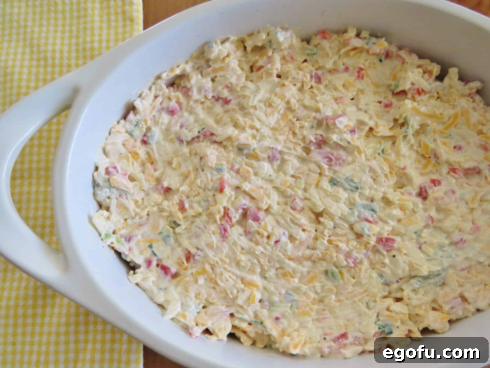 The smooth pimiento cheese dip mixture beautifully spread into an oval white baking dish, ready for its topping.