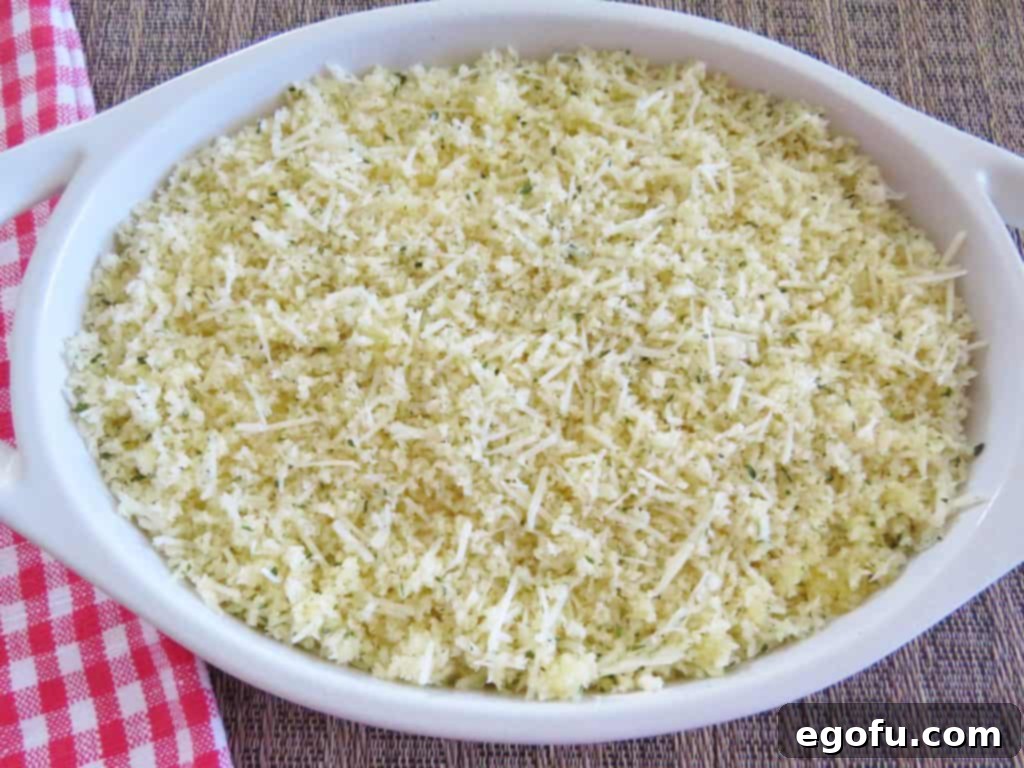 Baked Jalapeño Cheese Dip 9 Crumb topping mixture sprinkled on top of the creamy dip mixture in an oval baking dish, ready for the oven.