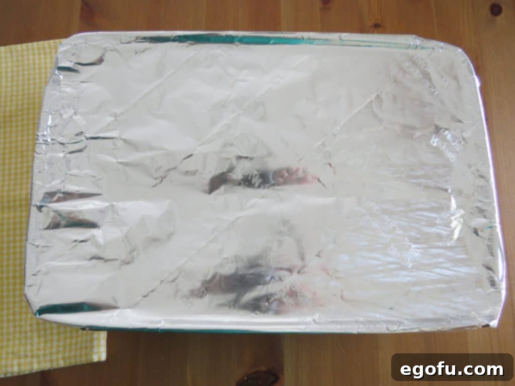 French toast casserole covered with aluminum foil, ready to be refrigerated overnight.