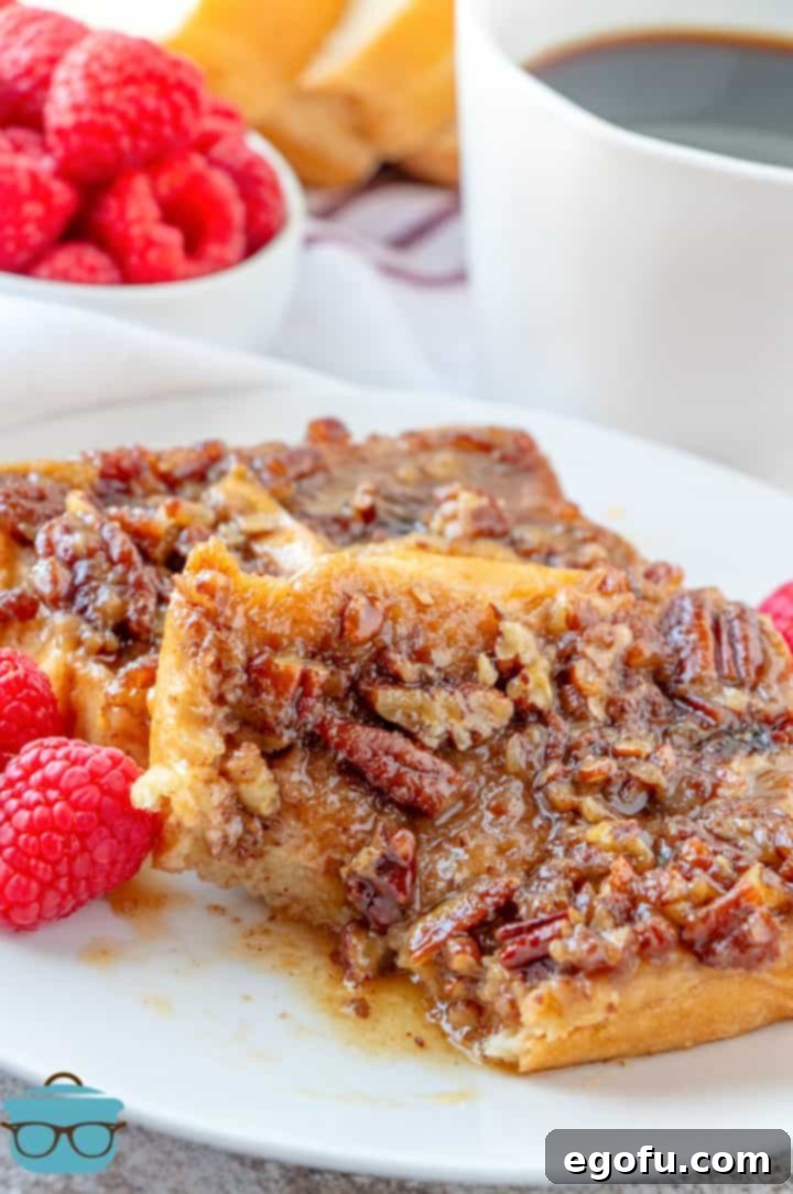 Two enticing slices of Pecan Praline French Toast Casserole on a plate, one with a bite taken, showcasing the delicious layers.