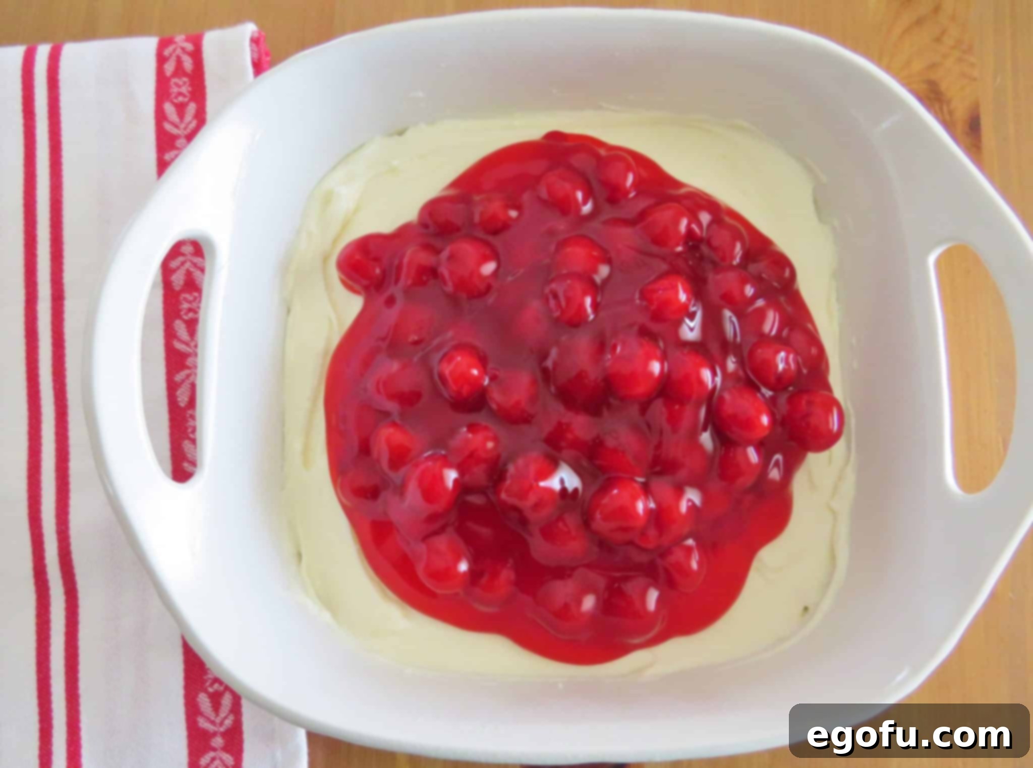 cherry pie filling spread onto cream cheese filling mixture in baking dish.