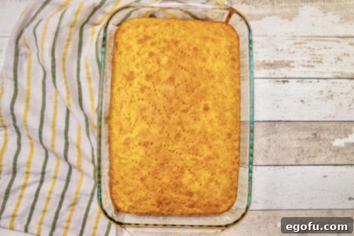 fully baked yellow cake with holes poked in it.
