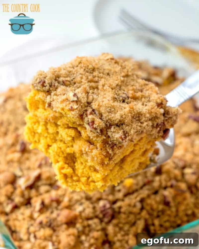 A slice of Pumpkin Pie Coffee Cake with streusel topping being lifted from the pan with a spatula.