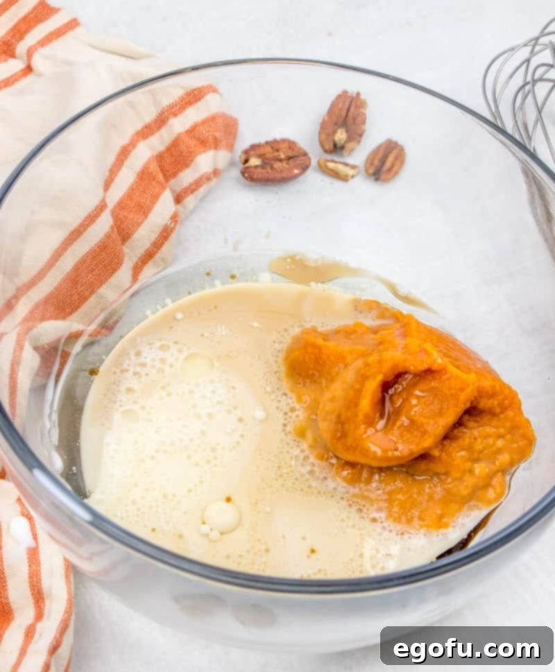 Pumpkin puree, vegetable oil, vanilla extract, and milk blended smoothly in a mixing bowl.