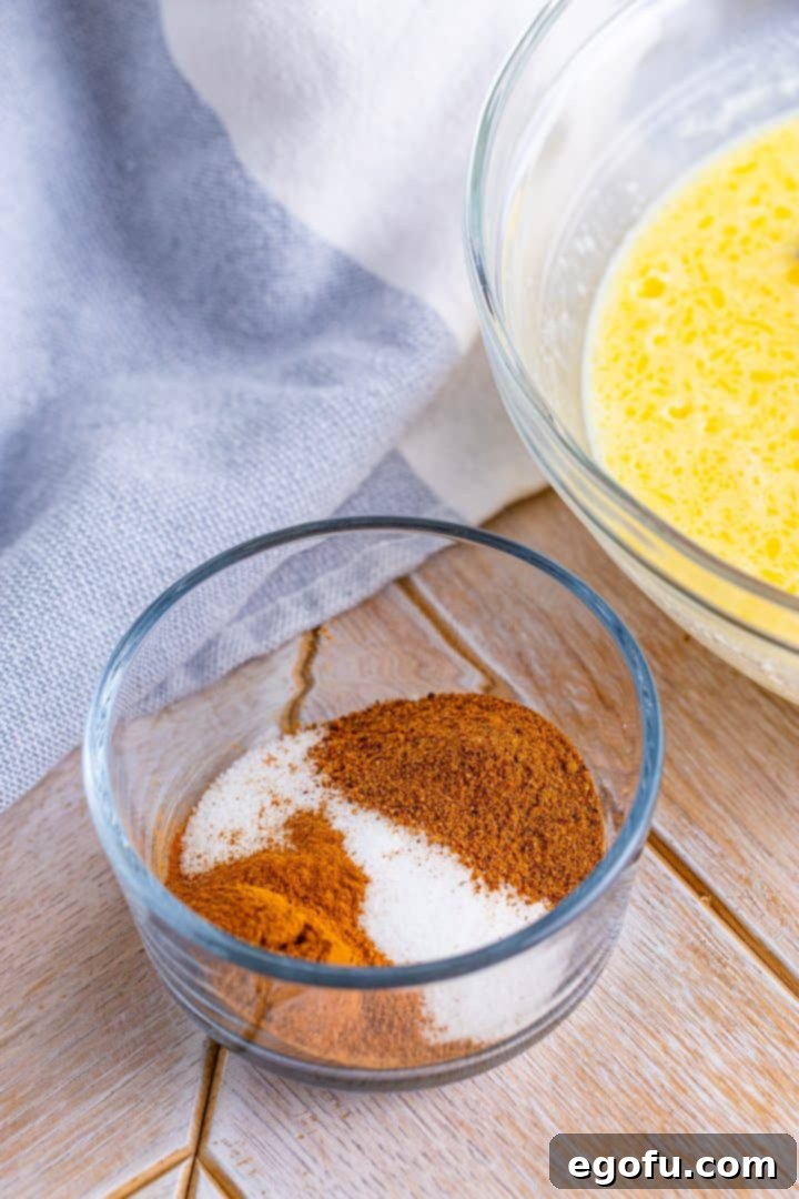 A small glass bowl contains a well-blended mixture of ground cinnamon, nutmeg, and granulated sugar, forming the aromatic coating for the French toast.