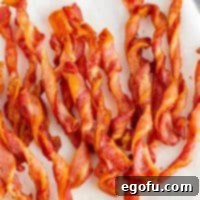 Crispy Air Fryer Bacon Spirals 8 Square image of Crispy Air Fryer Twisted Bacon on a white plate, ready to be served.